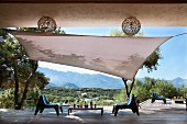 Mit Holzplanken ausgelegte Terrasse mit Sonnensegel, Olivenbäumen und modernen Stühlen aus Kunststoff