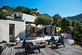 Terrasse eines mediterranen Bungalows mit Olivenbäumen und modernen Stühlen aus Kunststoff