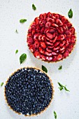 Two whole round fruit tarts with strawberries and blueberries (seen from above)
