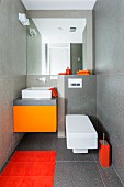 Designer-style guest toilet with grey-tiles walls and various orange accents