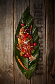 Fish with chilli and vegetables on a banana leaf (seen from above)
