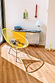 Yellow, retro, string easy chair with metal frame in front of 50s-style sideboard