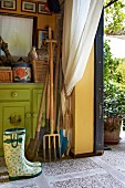Abstellraum mit Gartengeräten, angelehnt an bemalte, grüne Kommode