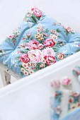 Romantic, pastel-blue seat cushion with pattern of roses