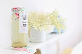 Holunderblüten und selbstgemachter Holunderblütensaft in romantisch verzierter Flasche