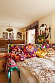 Sofa with various brightly patterned scatter cushions and blankets in comfortable, ethnic-style living room