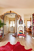 View into two rooms, pink cowhide rug, ethnic blanket on chair and painted archway