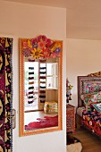 Ethnic-style bedroom with brightly painted mirror and patterned bed