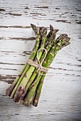 A bundle of asparagus on a white wooden surface