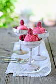 Three bowls of raspberry ice cream on a garden table