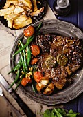 T-Bone-Steak mit Anchovisbutter, grünem Bohnen-Tomaten-Gemüse, Pommes Frites und Chermoula