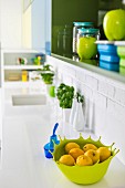 Blau- und Grüntöne im Hängeschrank und auf der Spülentheke einer weissen Küchenzeile