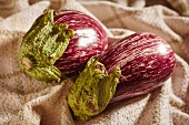 Two striped aubergines on a cloth