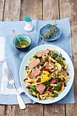 Penne pasta salad with roast beef, courgettes, dried tomatoes and spinach