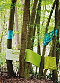 Green decorative fabric wrapped around trees in a forest