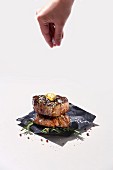 Hand streut grobes Salz auf Steak mit Kräuterbutter