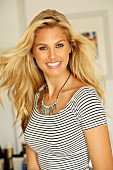 A laughing blonde woman wearing a striped top and a fashionable necklace