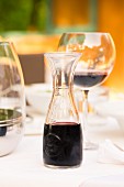 Red wine in a glass and a carafe on a laid table