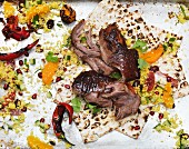 Lamb on unleavened bread with couscous, oranges and chilli peppers