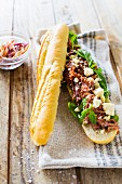 A pulled pork baguette with mustard sauce, basil and feta cheese