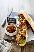 A baguette sandwich with roast pork fillet, bacon chutney, basil, mozzarella and chives