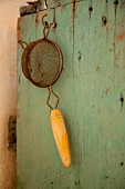 Vintage sieve hanging from wooden cabinet
