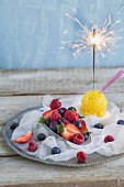 Mango sorbet with a sparkler and fresh raspberries, blueberries and strawberries