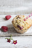 Himbeermuffin mit frischen Himbeeren und kleinen pinken Blüten