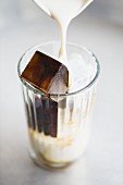 A glass with an espresso ice cube and milk