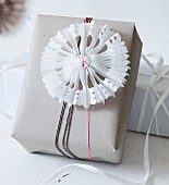Hand-made, pleated paper stars with cut-out patterns as festive decoration on wrapped gift