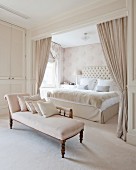 Chaise longue and sleeping alcove screened by curtains in glamorous bedroom