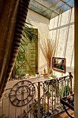 Glasdach mit Sonneneinfall in mediterranem Treppenhaus, schmiedeeisernes Geländer an Treppe, auf Sims Sammelsurium