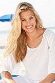 Junge blonde Frau in weisser Bluse am Strand