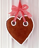 Gingerbread heart with simple iced trim hung from red and white gingham ribbon