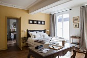 Schlafraum mit gelben Wänden, Doppelbett und antikem Schreibtisch