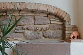 Rustikale Natursteinwand aus Sandstein und Backstein, Steinwaschbecken mit nostalgischen Armaturen