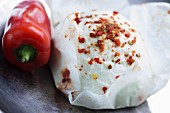 Spiced goat's cheese in cheese paper and a red pepper