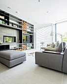 Large fitted shelving unit with integrated fireplace and firewood store in modern living room