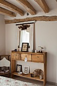 Rustikale Konsole aus Massivholz mit Schubladen in ländlichem Schlafzimmer mit Holzbalkendecke