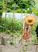 A woman wearing a mini mini dress and a straw hat putting on a pair of colourful panties