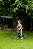 Frau in Unterwäsche und geblümter Bluse fährt Fahrrad