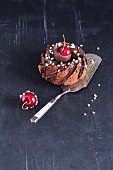 A mini cakes with chocolate glaze, almonds and chocolate-coated cherries
