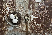 An Easter nest with eggs and feathers on an antique metal surface