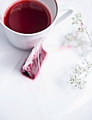 Benutzter Teebeutel neben Tasse mit Früchtetee