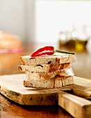 Four slices of olive bread with red chilli on a wooden board