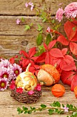Autumnal still-life arrangement with squash, leaves & flowers