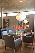Dining area with glass dining table and upholstered chairs, pendant light above