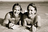 Twin brothers lying in the sea on a beach (second photo)