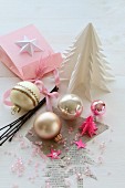 Weihnachtskugeln und rosa Perlen zwischen selbstgemachten Weihnachtsbäumchen aus Papier