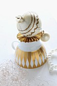 Upturned, vintage teacup with gold pattern and hand-painted Christmas bauble on origami paper star